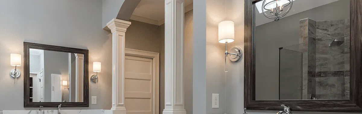 A gray bathroom with custom wall sconces lighting.