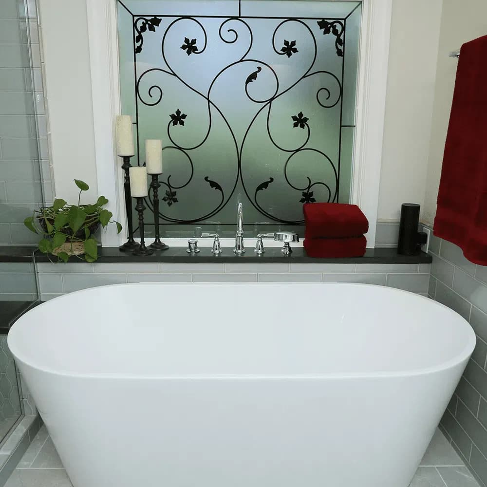 A free-standing soaking tub in front of a window with privacy glass.