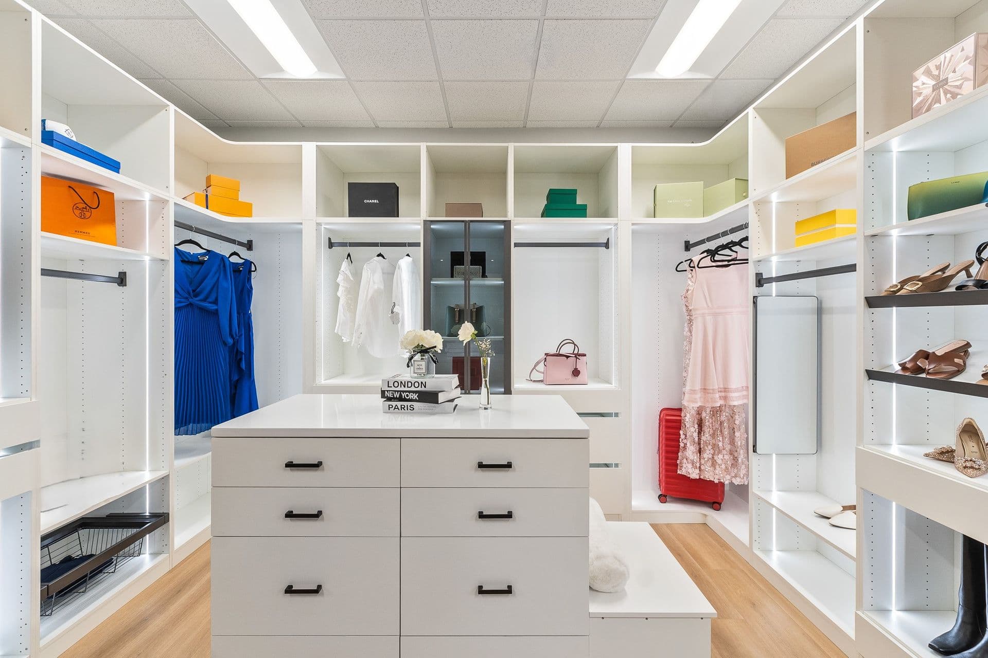 A large walk-in closet with built-in white shelving and central island with drawers.