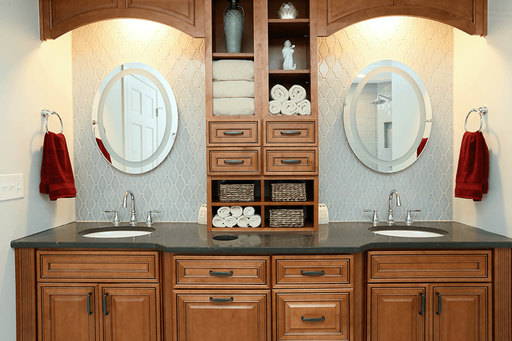 A custom built double vanity with built-in storage shelves and drawers, dark countertop, and brown cabinets.