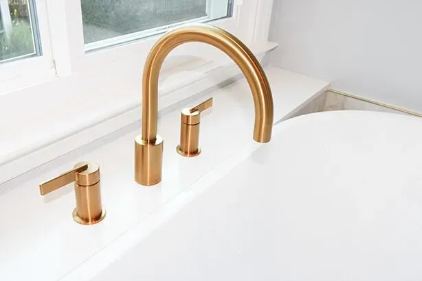 A kitchen sink with gold-colored faucet.