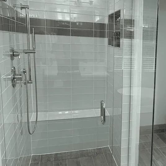 A walk-in shower with glass doors, custom tile walls, and a built-in bench.
