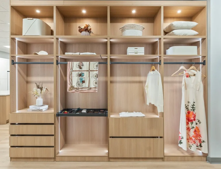 Custom walk-in closet in Raleigh NC with oak-finish cabinetry, built-in drawers, adjustable shelving, hanging rods, accessory storage, and integrated lighting